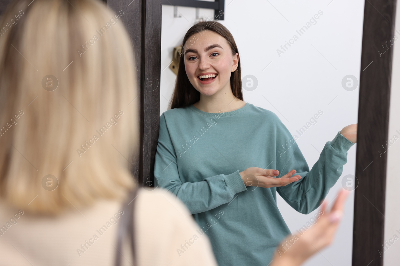 Photo of Happy woman welcoming guest to her apartment