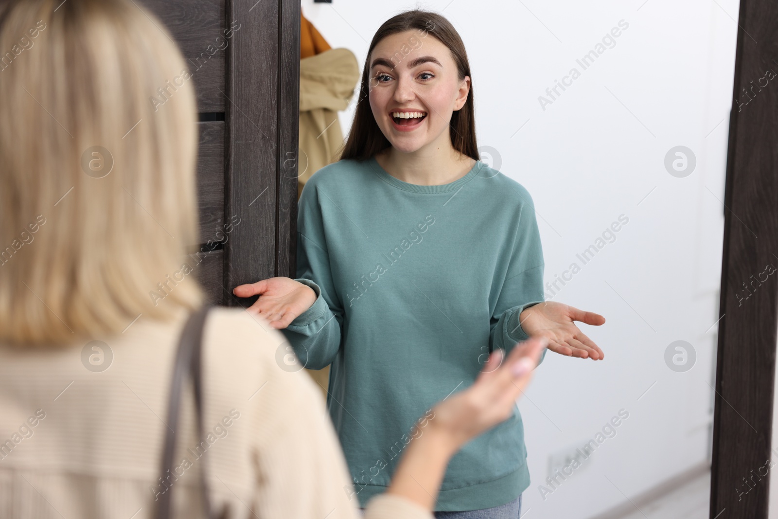 Photo of Happy woman welcoming guest to her apartment