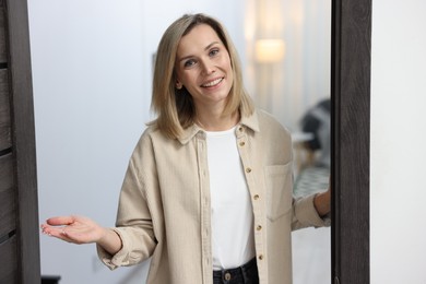 Cheerful woman welcoming guests to her apartment