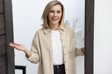 Photo of Cheerful woman welcoming guests to her apartment