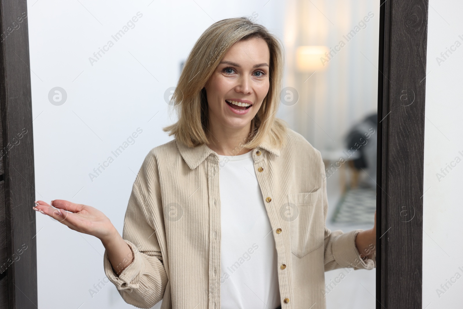 Photo of Cheerful woman welcoming guests to her apartment