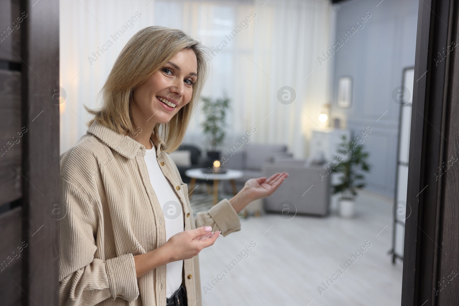 Photo of Cheerful woman welcoming guests to her apartment