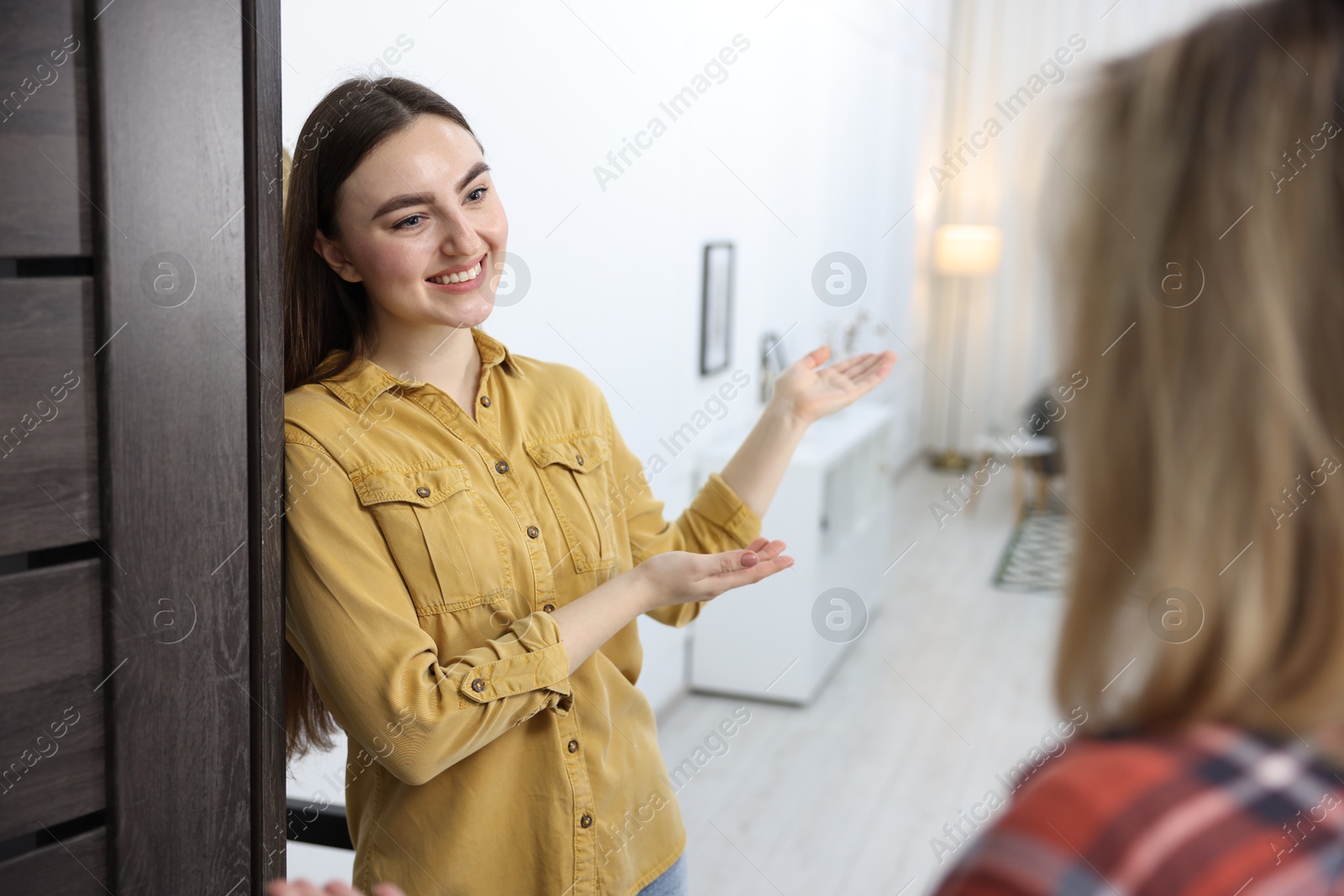 Photo of Happy woman welcoming friend to her apartment