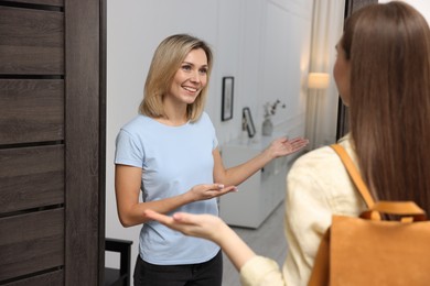 Photo of Cheerful woman welcoming friend to her house