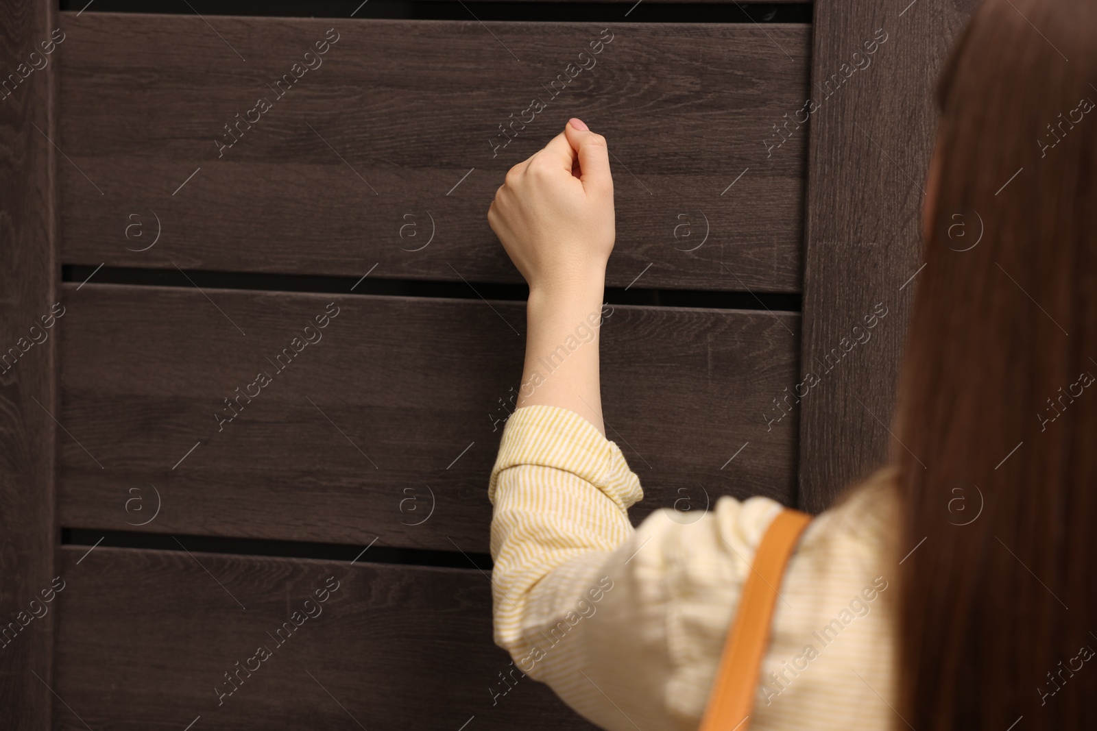 Photo of Woman knocking on door of her friends apartment, closeup