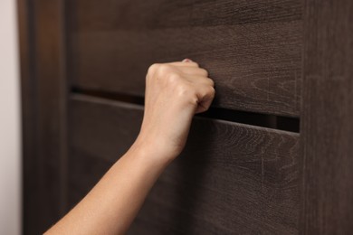 Woman knocking on door of her friends apartment, closeup