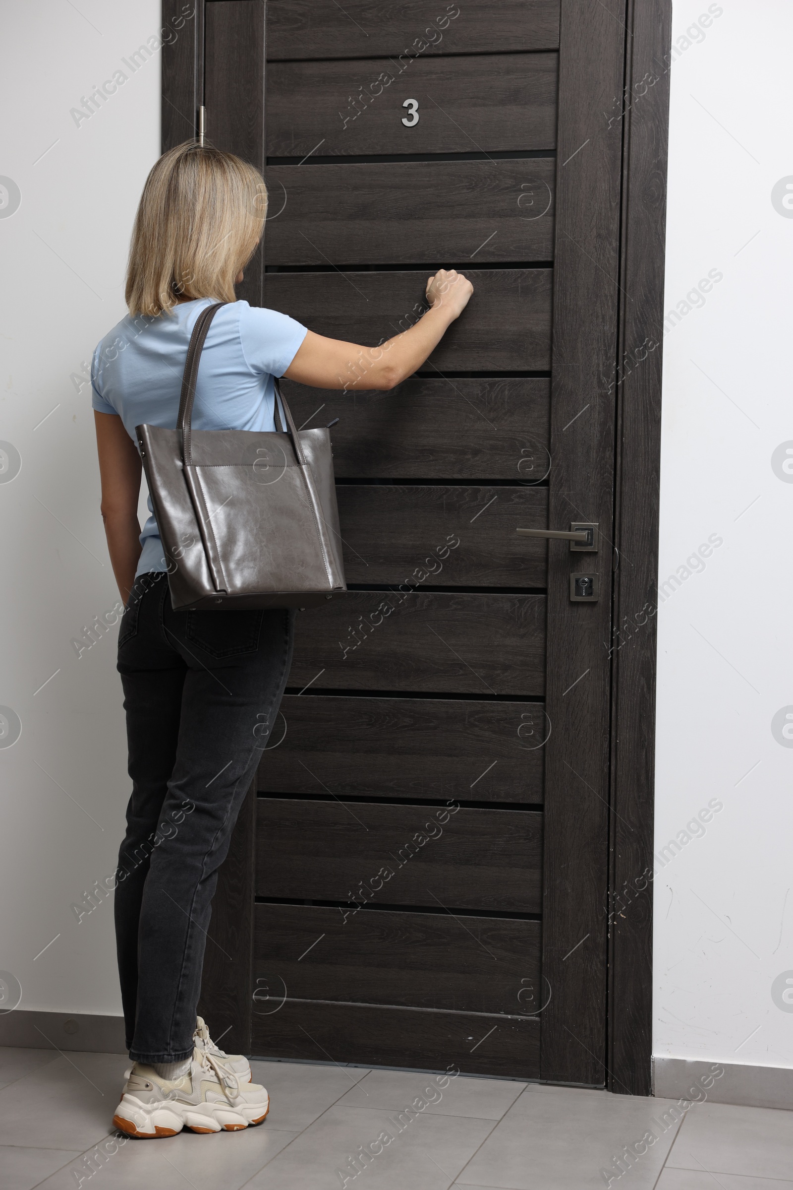 Photo of Woman knocking on door of her friends apartment