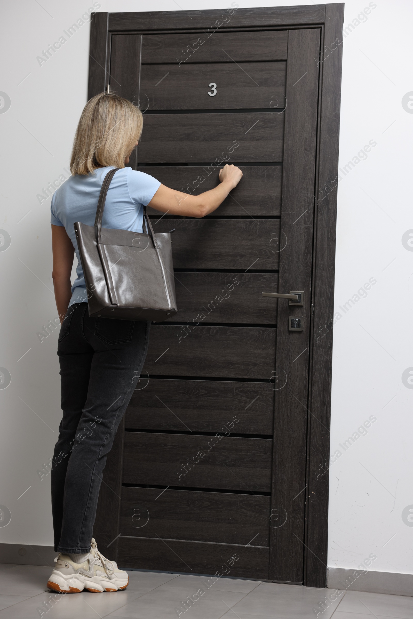 Photo of Woman knocking on door of her friends apartment