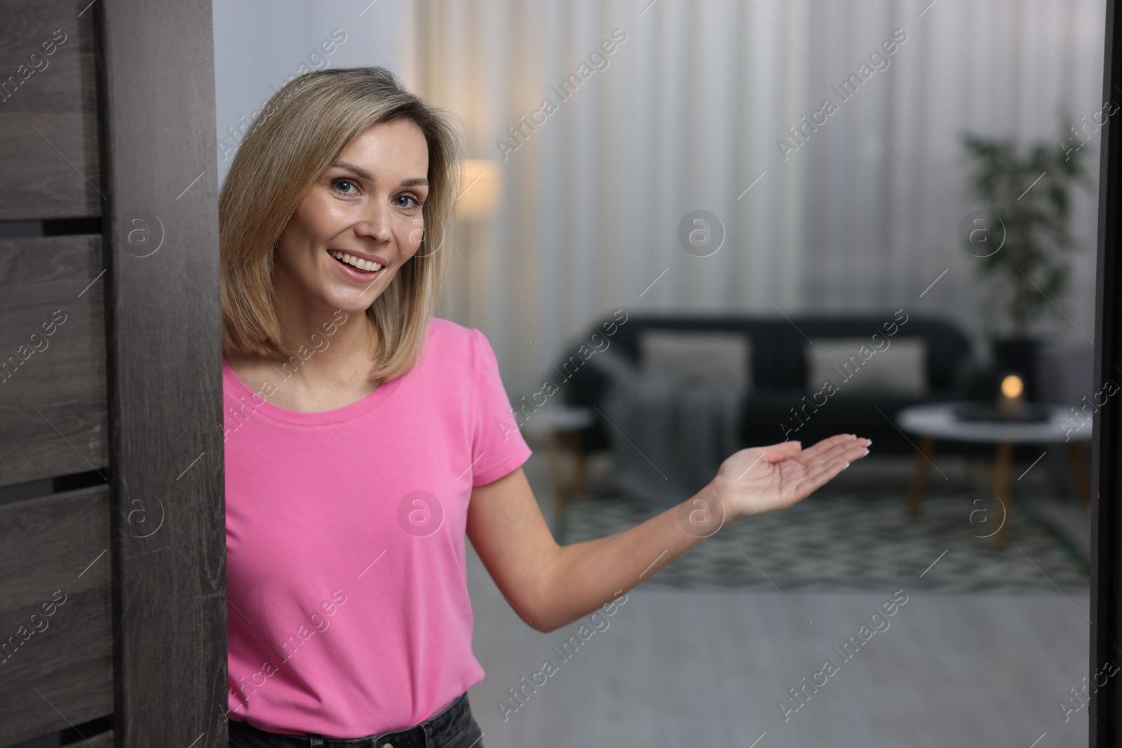 Photo of Happy woman welcoming guests to her house