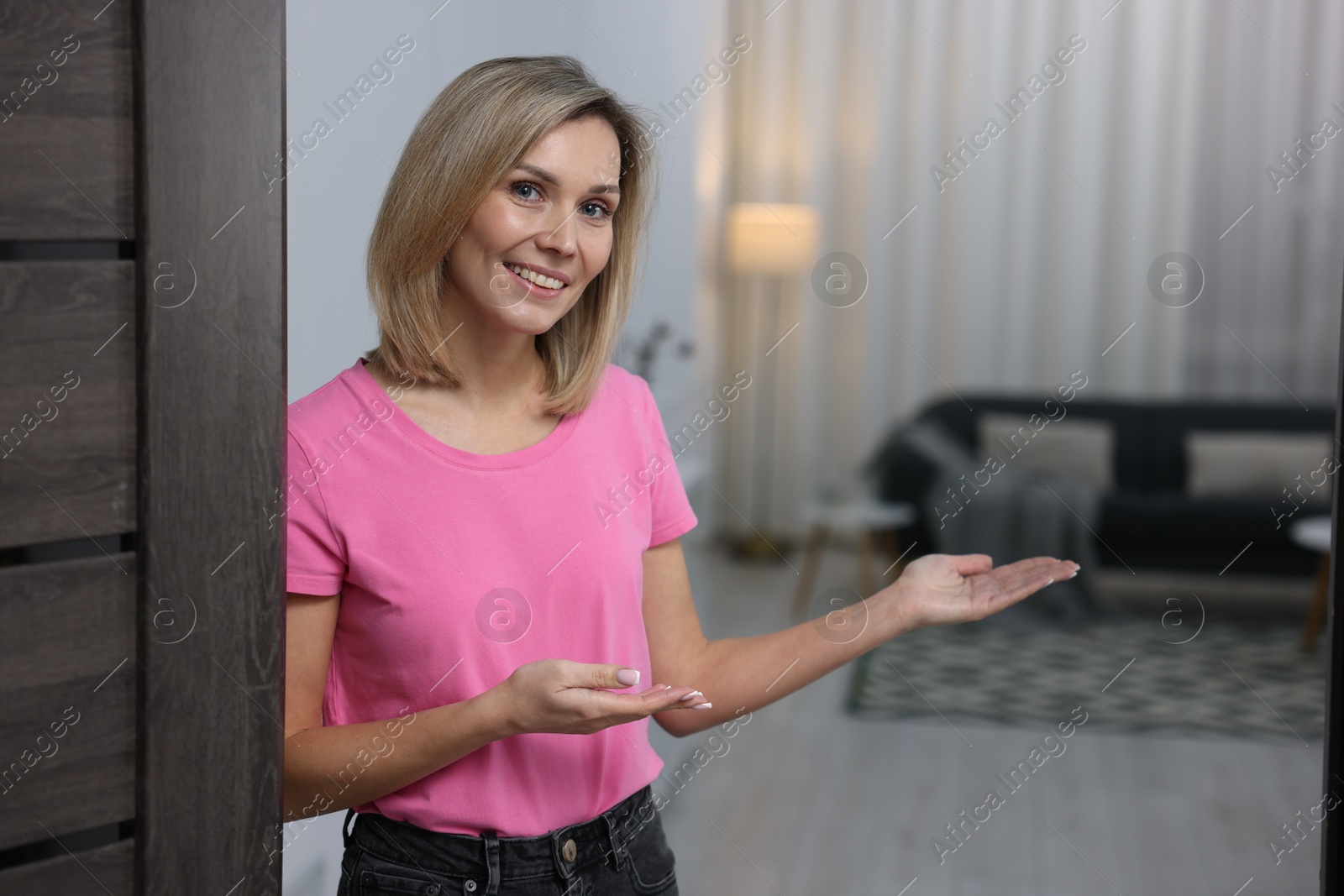 Photo of Happy woman welcoming guests to her house