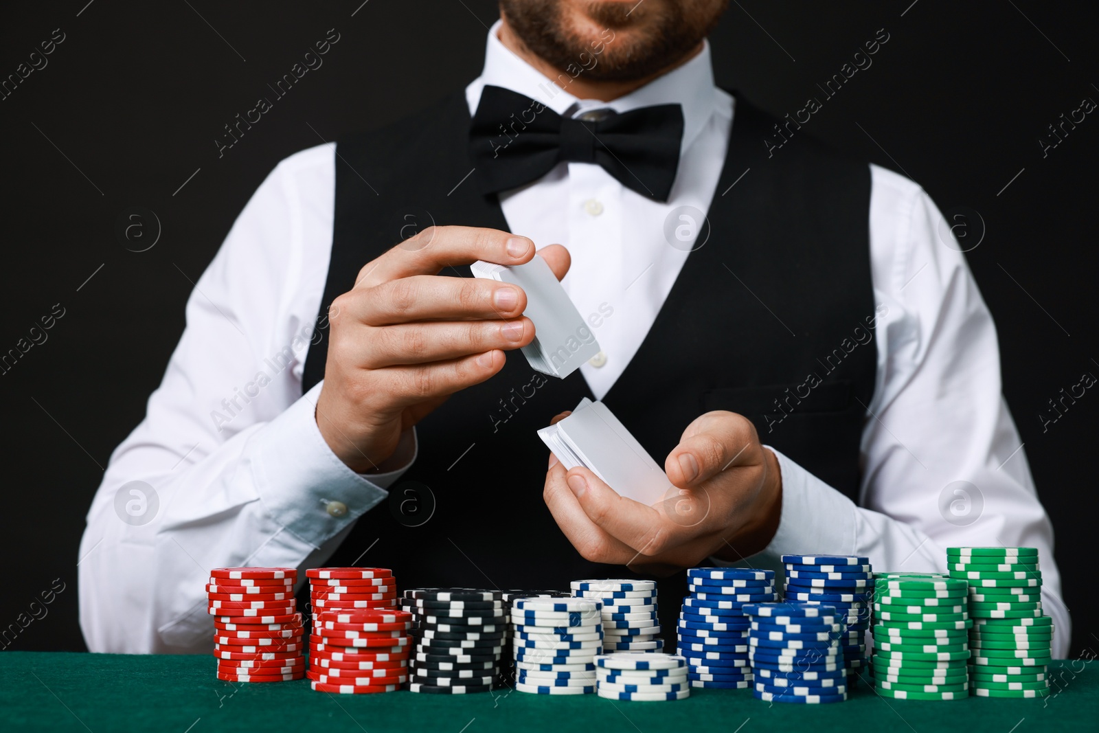 Photo of Professional croupier shuffling cards at gambling table, closeup