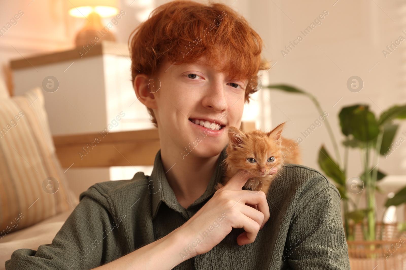 Photo of Redhead teenage boy with cute ginger kitten indoors