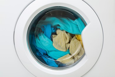 Photo of Washing machine with laundry as background, closeup