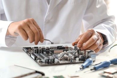 Photo of Man installing computer chip onto motherboard at white table, closeup