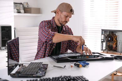 Photo of Man fixing computer monitor at white table