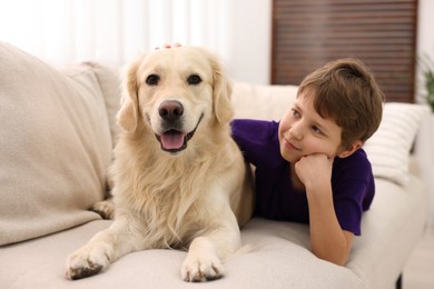 Photo of Boy with his cute dog on sofa at home