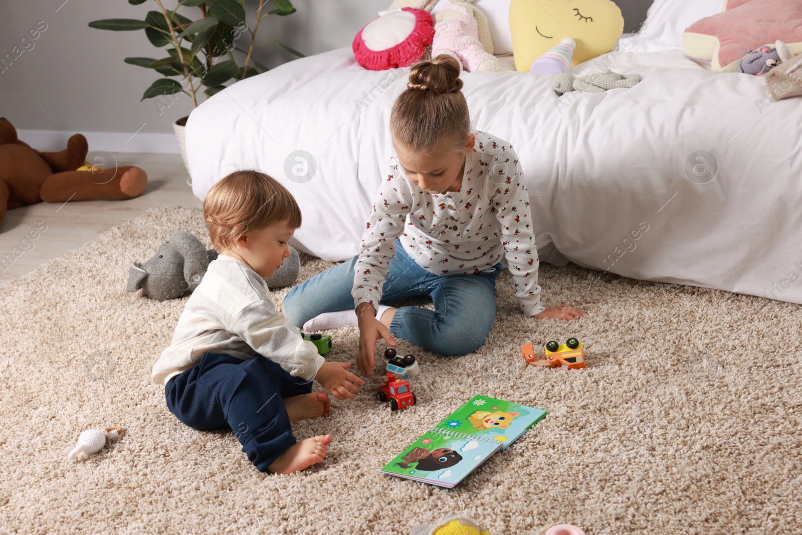 Photo of Sister and brother playing with toy cars on floor indoors