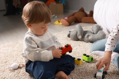 Photo of Sister and brother playing with toy cars on floor indoors