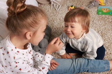 Photo of Sister and brother spending time together on floor at home