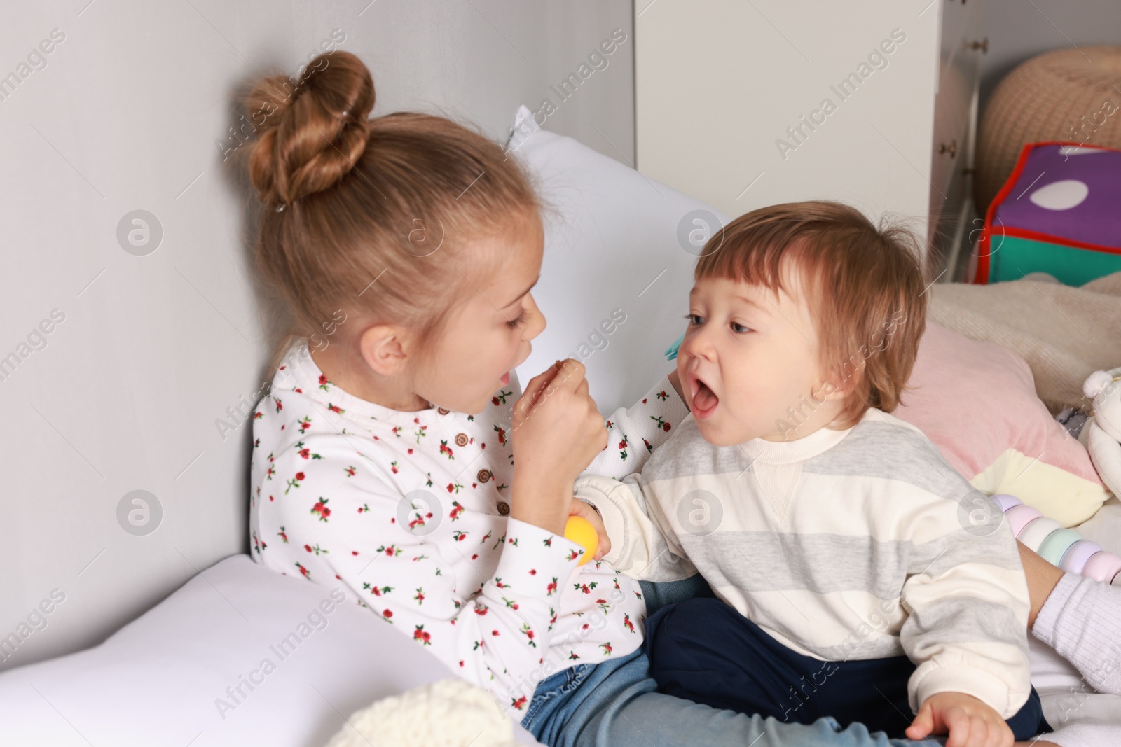 Photo of Sister and brother playing together on bed indoors