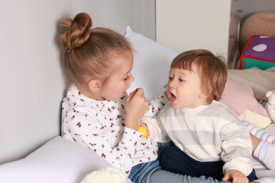 Photo of Sister and brother playing together on bed indoors