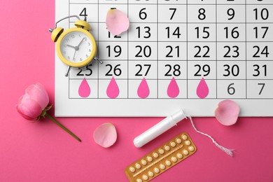 Photo of Flat lay composition with calendar and menstrual products on pink background