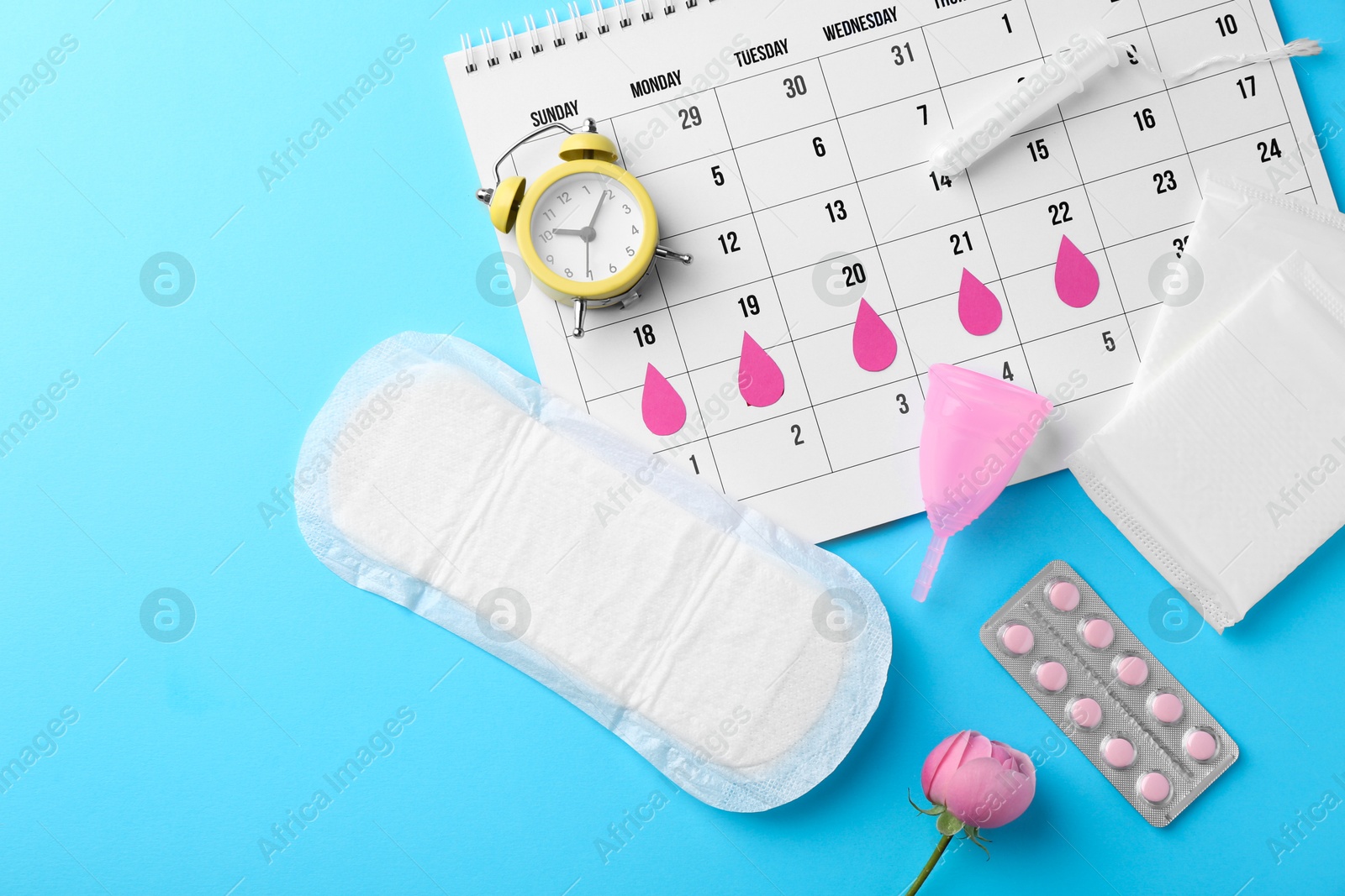 Photo of Flat lay composition with calendar and menstrual products on light blue background