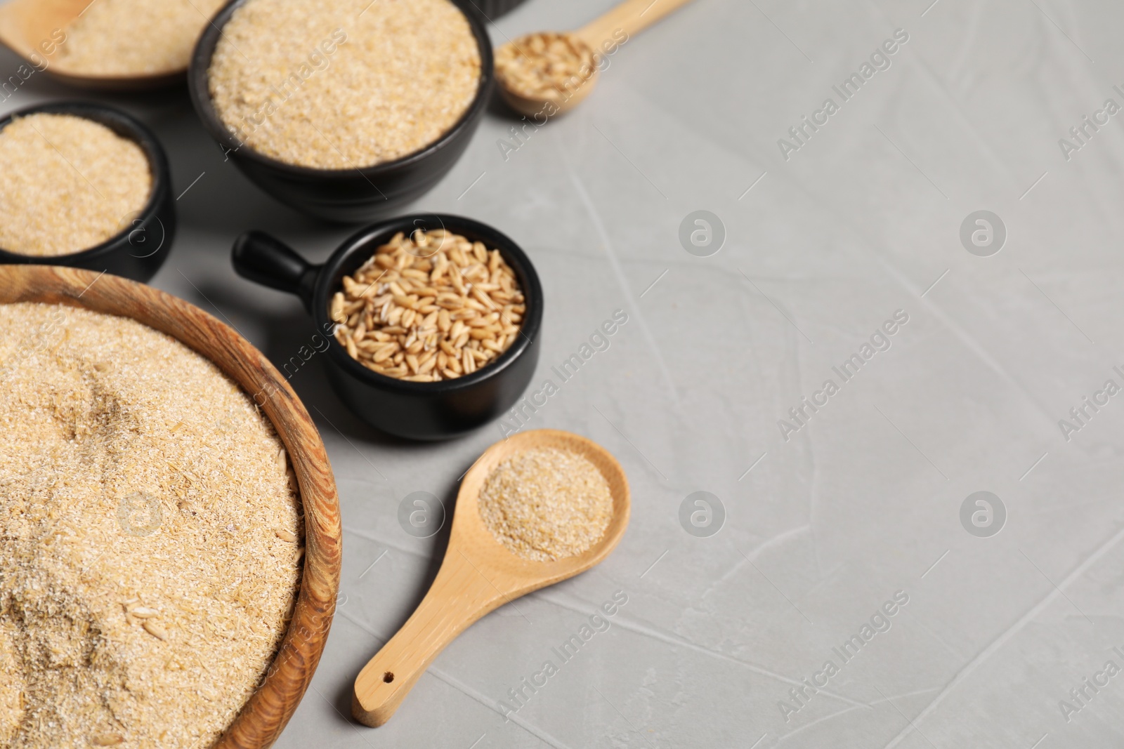 Photo of Oat bran and grains on grey table, closeup. Space for text