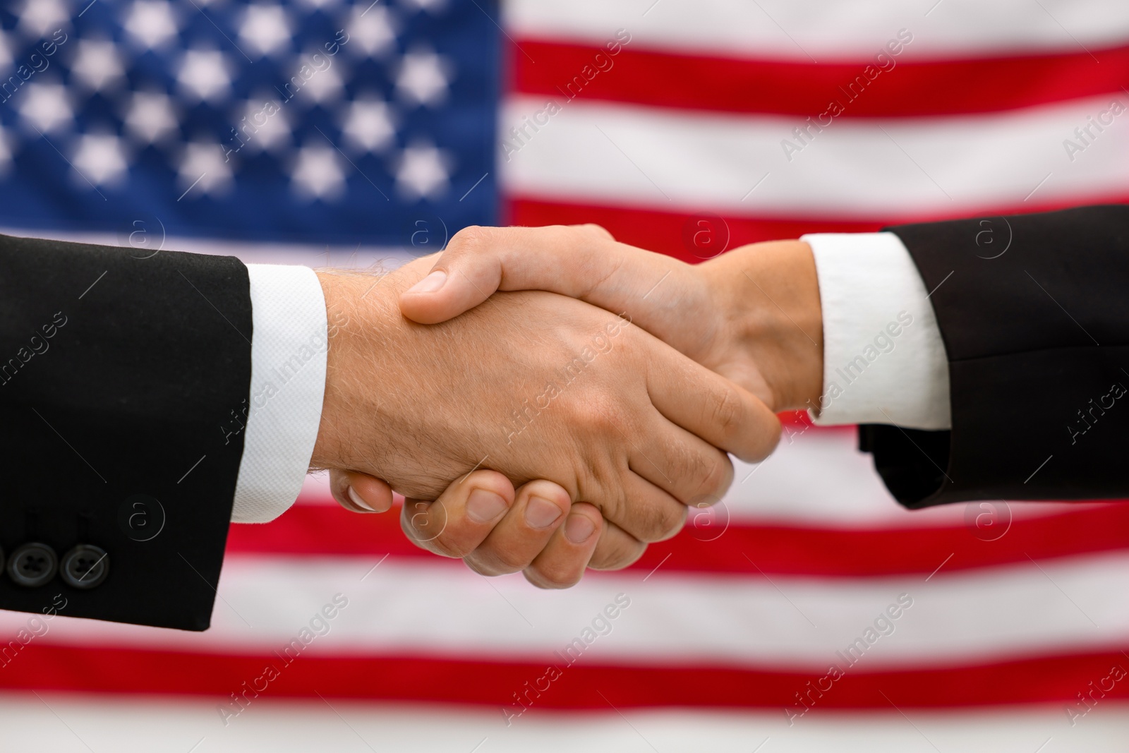 Photo of Diplomats shaking hands against flag of USA, closeup