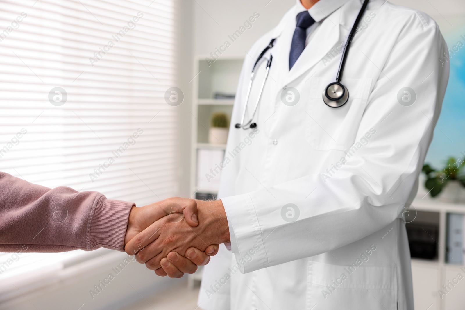 Photo of Doctor shaking hands with patient in hospital, closeup