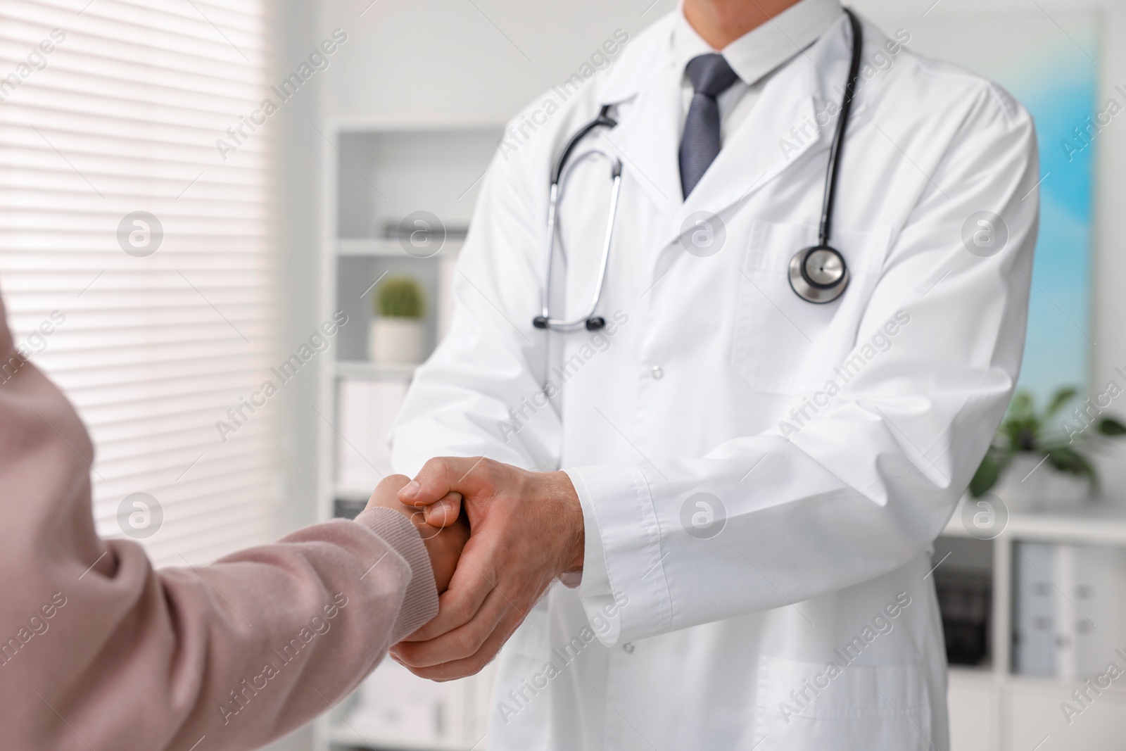 Photo of Doctor shaking hands with patient in hospital, closeup