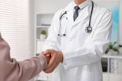 Doctor shaking hands with patient in hospital, closeup