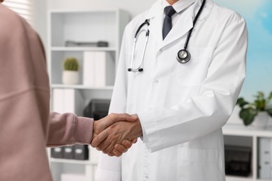 Photo of Doctor shaking hands with patient in hospital, closeup