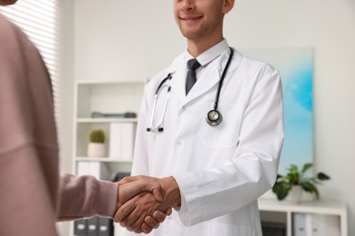 Photo of Doctor shaking hands with patient in hospital, closeup