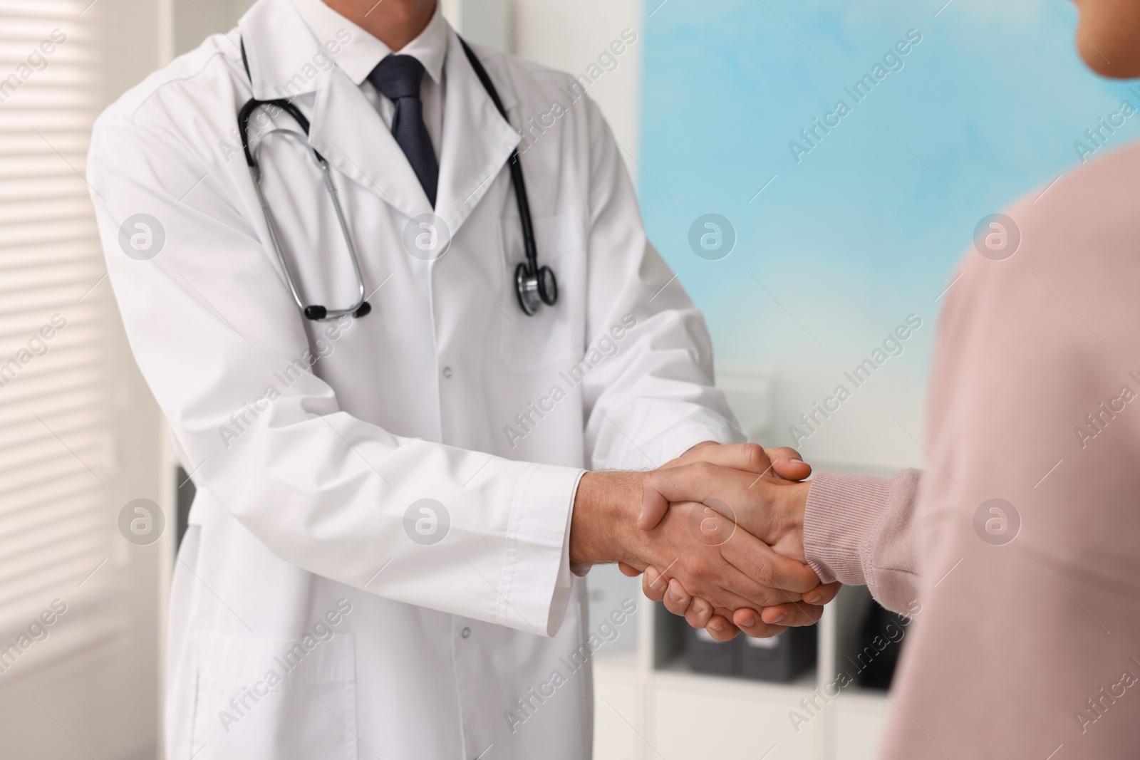 Photo of Doctor shaking hands with patient in hospital, closeup