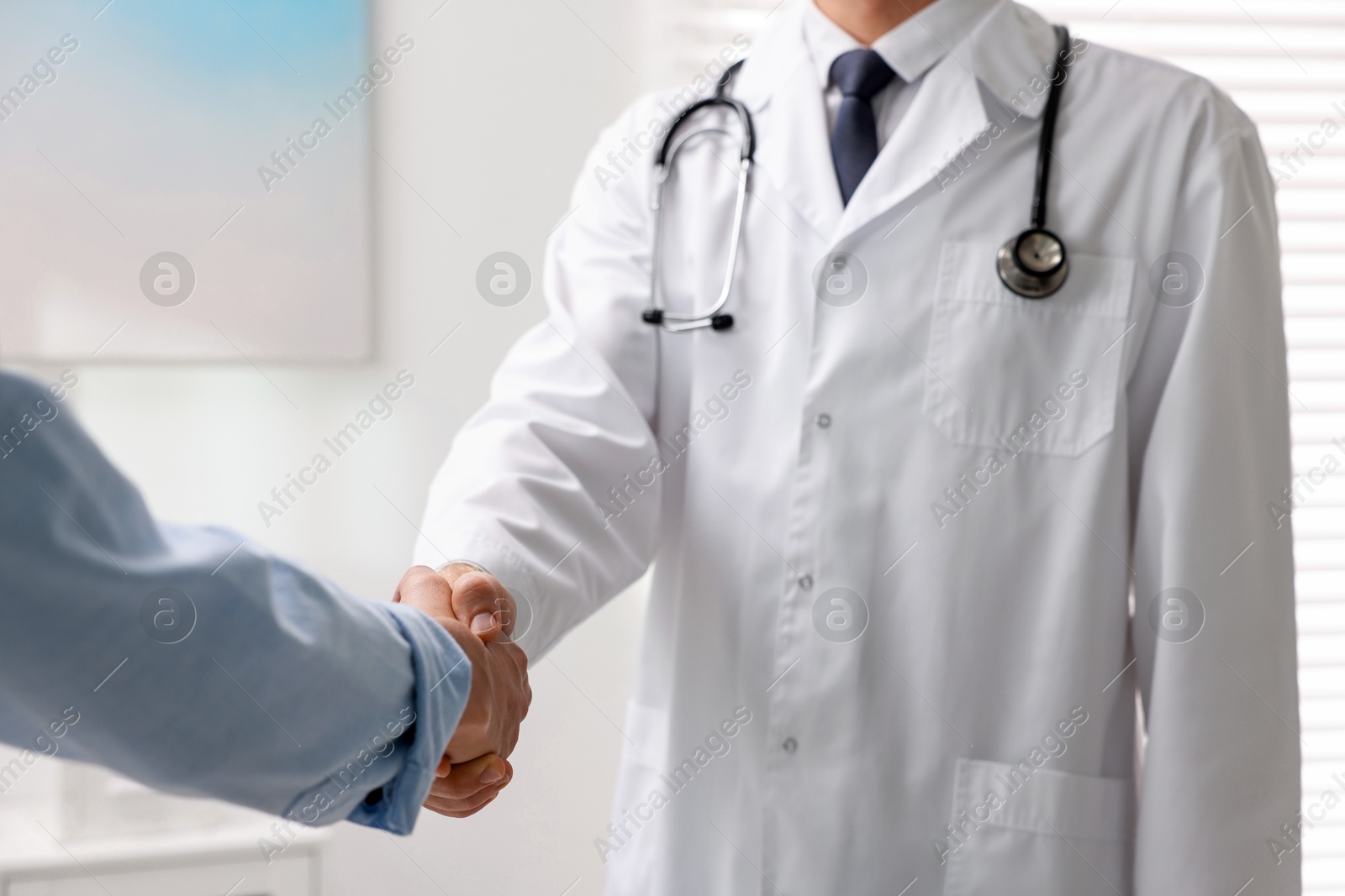 Photo of Doctor shaking hands with patient in hospital, closeup