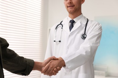 Doctor shaking hands with patient in hospital, closeup