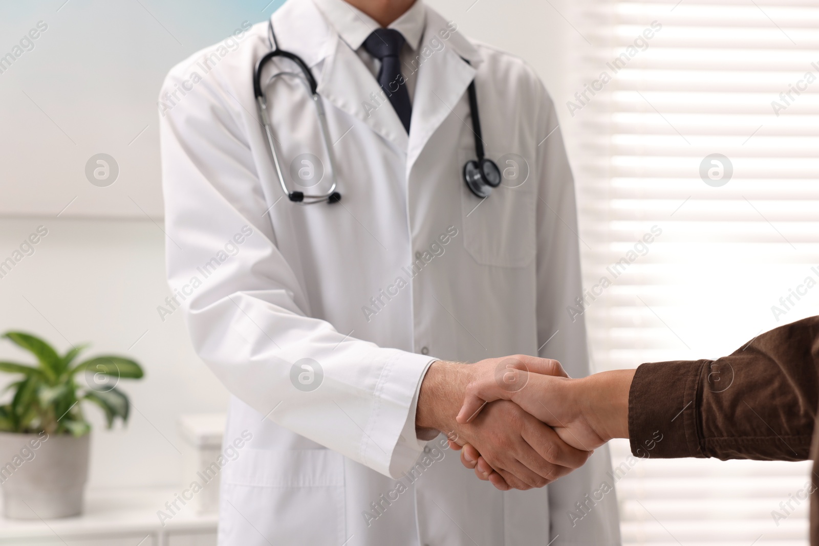 Photo of Doctor shaking hands with patient in hospital, closeup