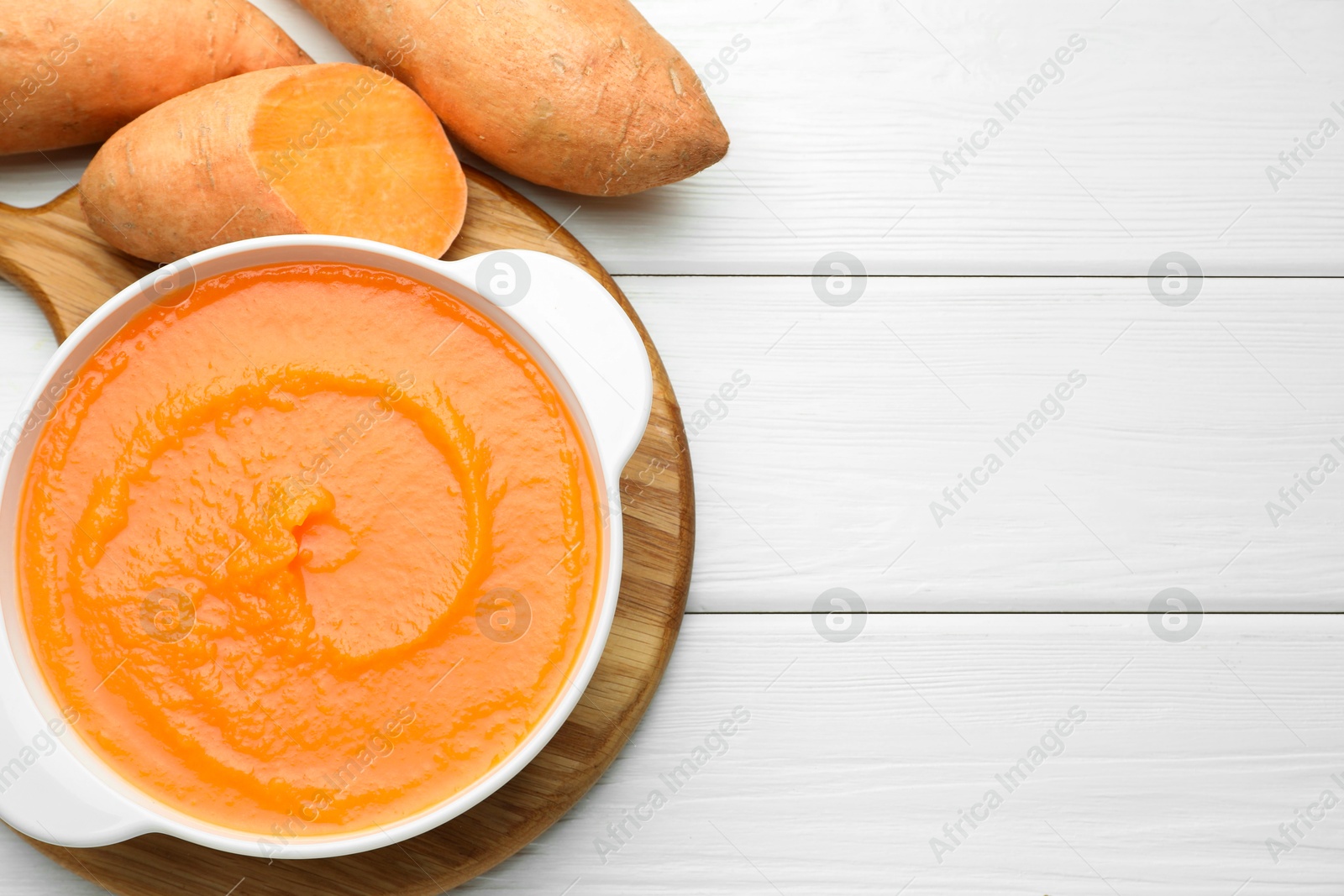 Delicious sweet potato soup with fresh vegetables on white wooden table, top view. Space for text Photo of Delicious sweet potato soup with fresh vegetables on white wooden table, top view. Space for text