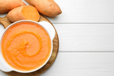 Photo of Delicious sweet potato soup with fresh vegetables on white wooden table, top view. Space for text