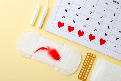 Photo of Flat lay composition with calendar and menstrual products on beige background