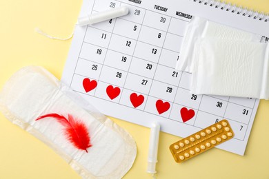 Photo of Flat lay composition with calendar and menstrual products on beige background