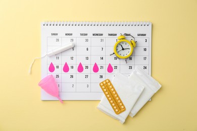 Photo of Flat lay composition with calendar and menstrual products on beige background