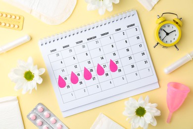 Photo of Flat lay composition with calendar and menstrual products on beige background