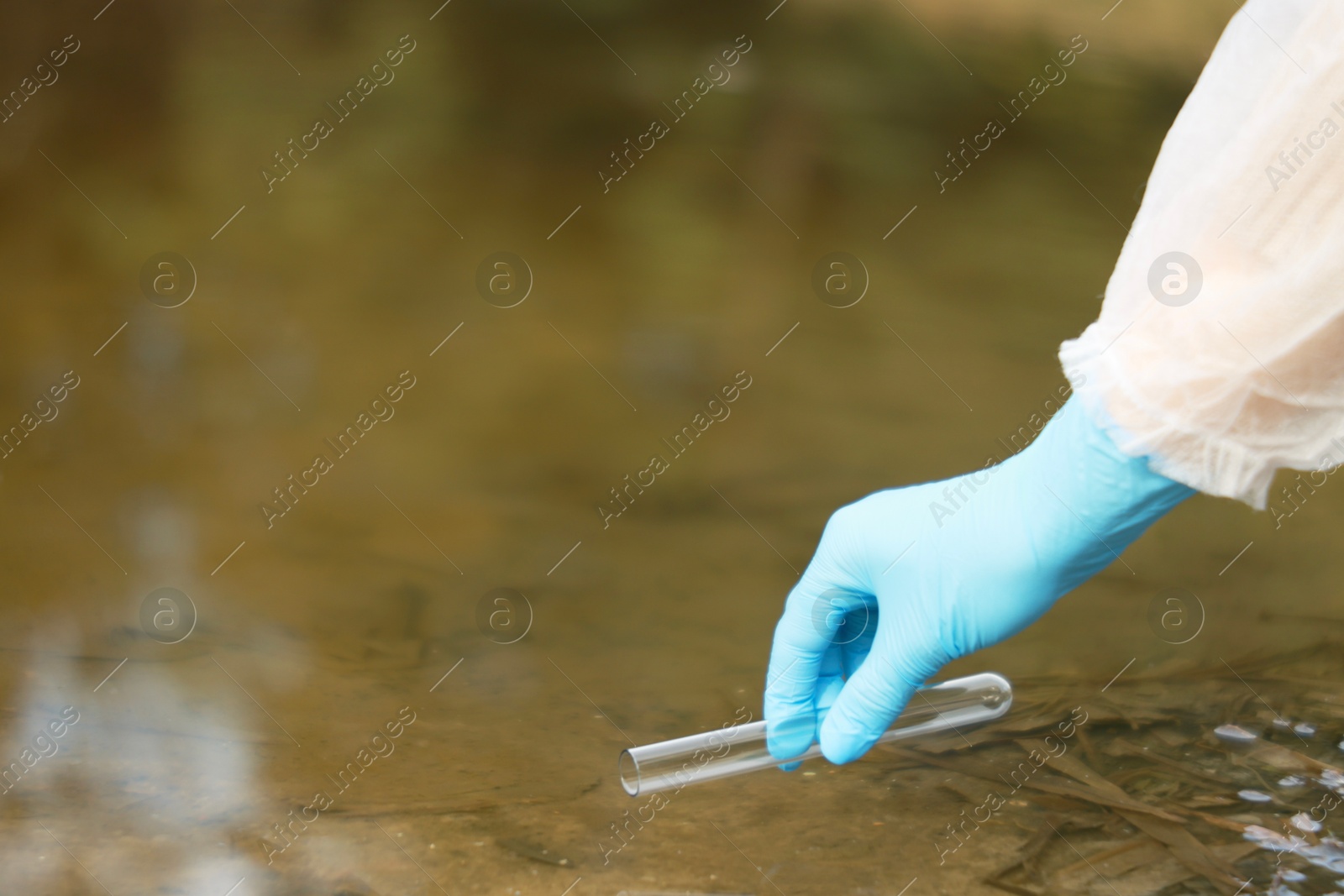 Photo of Examination of water quality. Researcher taking water sample from lake outdoors, closeup. Space for text