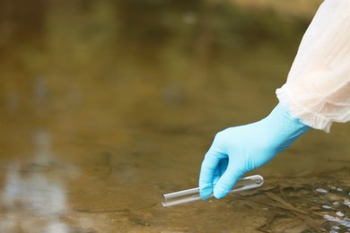 Photo of Examination of water quality. Researcher taking water sample from lake outdoors, closeup. Space for text