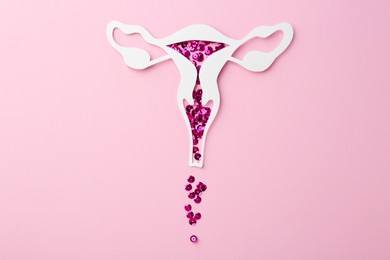 Photo of Menstruation. Paper uterus with sequins on pink background, top view