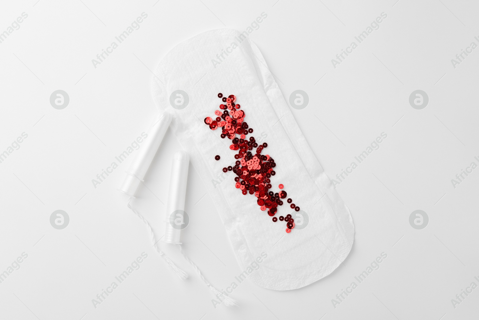 Photo of Menstrual pad with red sequins and tampons on white background, top view