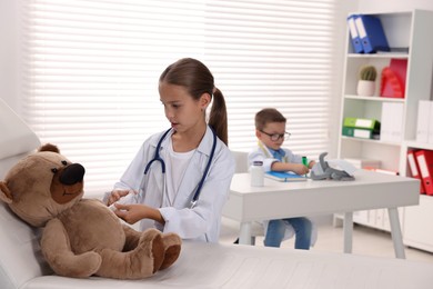 Photo of Little boy and girl with toy pretending to be doctors indoors