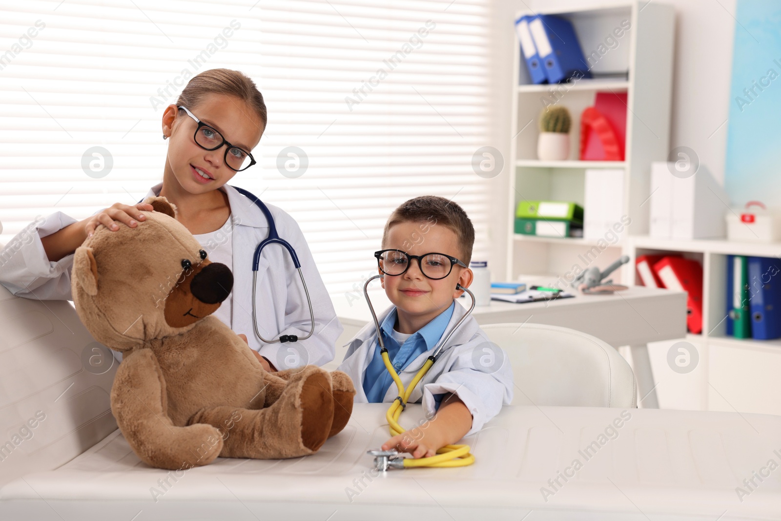 Photo of Little boy and girl with toy pretending to be doctors indoors